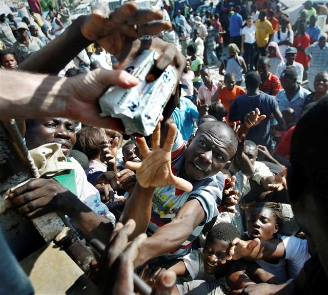 2010년 1월 아이티 지진 참사 후 주민들이 구호 트럭에서 나눠 주는 식량을 서로 먼저 잡으려고 팔을 뻗고 있다. AP 연합뉴스