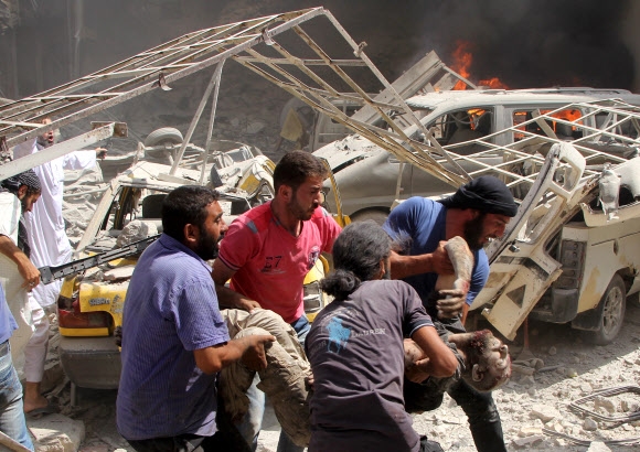 시리아 반군 점령지인 북부 이들리브의 한 상가터에서 10일(현지시간) 현지인들이 정부군 추정 전투기의 공습으로 희생된 주민 시신을 옮기고 있다. 이들리브 AFP 연합뉴스