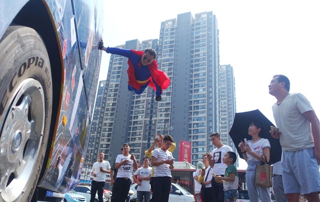 12일(현지시간) 중국 뤄양에서 열린 ‘제1회 뤄양 국제 마술 페스티벌’에서 슈퍼맨 복장을 한 남자가 버스에 손을 대고 하늘을 날아 버스와 함께 이동하는 마술을 선보이고 있다.  사진=TOPIC/Splash News
