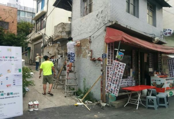 20일 서울 용산구의 지역융합형 녹화사업지로 선정된 서계동 개미슈퍼의 낡은 벽면을 시민들이 새로 칠하고 있다. 용산구 제공