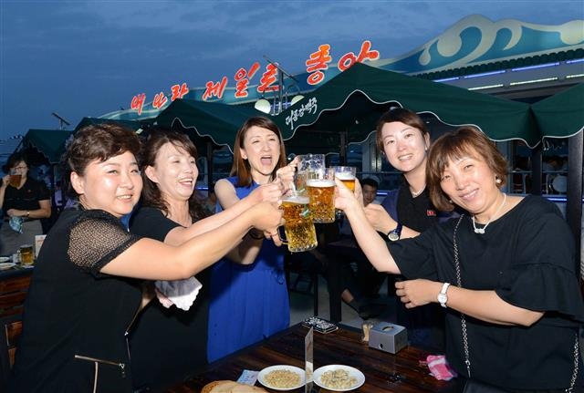 지난 8월 12일 열린 북한 평양 대동강맥주축제에서 북한 주민들이 대동강맥주잔을 부딪치며 즐거운 표정을 짓고 있다.  연합뉴스