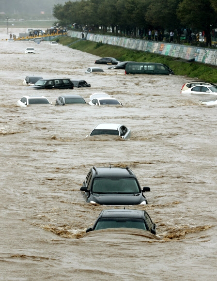 5일 오후 경북 경주시 서천둔치 주차장에 있던 차들이 갑자기 불어난 물에 떠내려가고 있다.  연합뉴스