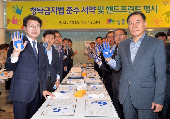 12일 서울 성동구 행당동 성동구청에서 열린 청탁금지법 준수 서약 및 핸드프린팅 행사에 참석한 정원오(앞줄 왼쪽) 성동구청장과 간부 공무원 50여명이 본인의 손도장을 찍은 서약서를 들고 청렴한 성동구를 만들겠다는 의지를 다지고 있다.  손형준 기자 boltagoo@seoul.co.kr