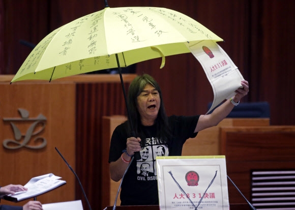 홍콩 민주파 입법회(국회) 의원 렁&#53245;훙이 12일 홍콩 입법회당에서 열린 입법회 개회 선서식에서 민주혁명의 상징인 노란 우산을 든 채 중국이 내년에 실시될 행정장관 직접선거에 개입하는 것을 비판하고 있다.  홍콩 AP 연합뉴스