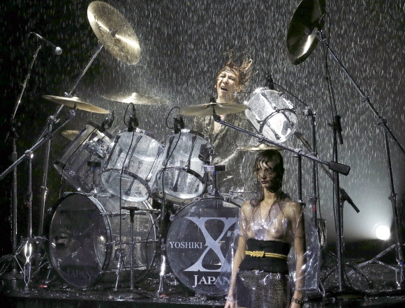 한 모델이 17일(현지시간) 일본에서 열린 ‘도쿄 패션위크 2017 봄/여름 콜렉션’ 오프닝 중 일본 뮤지션 요시키가 드럼을 연주하는 동안 그가 디자인한 작품을 선보이고 있다. AP 연합뉴스