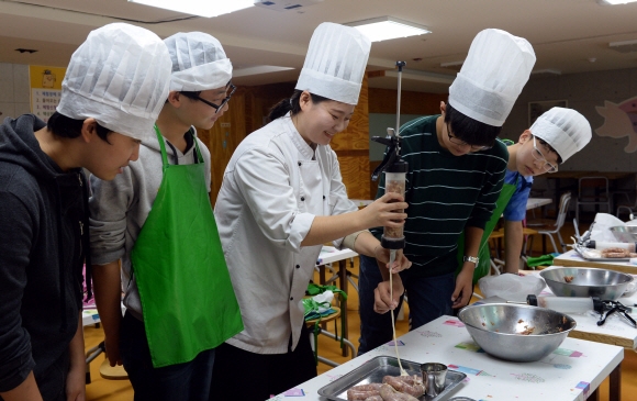학생들이 돼지문화 체험실습장에서 소시지 만드는 법을 배우고 있다.