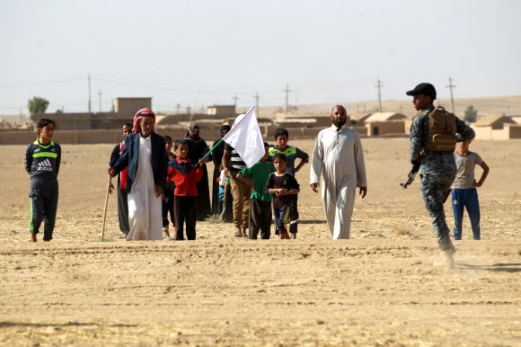 이슬람국가(IS)가 장악한 이라크 북부 모술에서 탈출한 주민들이 18일(현지시간) 모술 남쪽 30㎞ 지점의 바와니야에서 백기를 든 채 이라크 정부군에게 다가가고 있다. 바와니야 AFP 연합뉴스