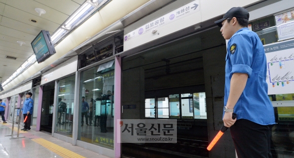 19일 오전 스크린도어에 승객이 끼여 숨지는 사고가 발생한 서울 지하철 5호선 김포공항역에서 도시철도공사 직원들이 사고 수습을 위해 열어 놓은 스크린도어 주변을 통제하고 있다. 손형준 기자 boltagoo@seoul.co.kr