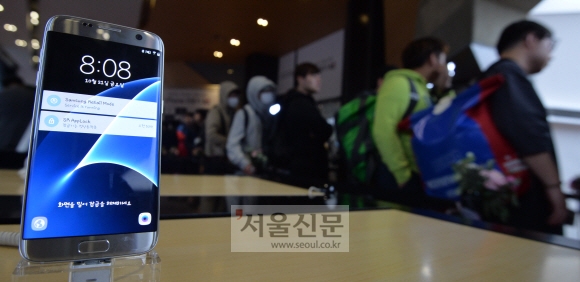 아이폰7 판매일인 21일 서울 광화문 KT올레스퀘어에 전시된 삼성 갤럭시S7 너머로 개통을 위해 줄을 선 시민들이 보이고 있다. 박지환 기자 popocar@seoul.co.kr