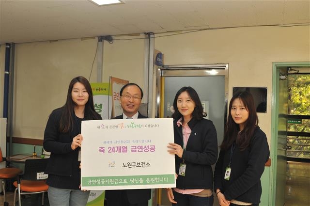 24개월 금연에 성공한 유희정(왼쪽 두 번째)씨가 25일 서울 노원구보건소에서 현금 인센티브를 받은 뒤 금연 상담사들과 포즈를 취하고 있다. 노원구 제공