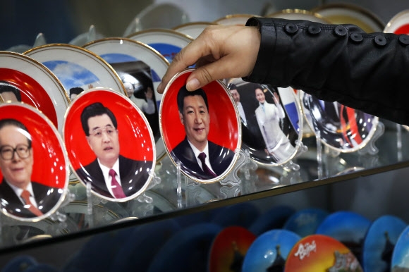 중국 베이징 천안문 스퀘어의 한 매장에서 시진핑 중국 주석의 얼굴이 새겨진 도자기 그릇을 매점 직원이 집어들고 있다. 왼편에 장쩌민과 후진타오 전 주석의 얼굴도 보인다.  2016-10-27 AP 연합뉴스