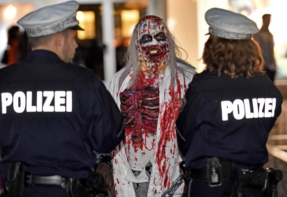 31일(현지시간) 독일 에센에서 핼러윈 데이를 맞아 열린 ‘좀비 워크(zombie walk)’ 행사에서 끔찍한 좀비 분장을 한 참가자가 경찰들과 대화를 나누고 있다. AP 연합뉴스