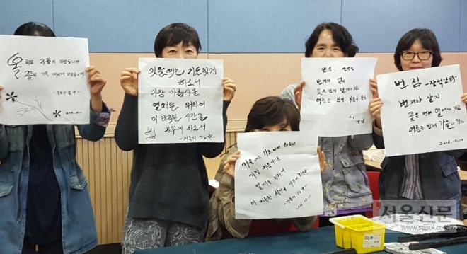 캘리그라피를 배우는 수강생들이 손으로 그린 그림 문자를 들어 보이고 있다. 과천시 제공 