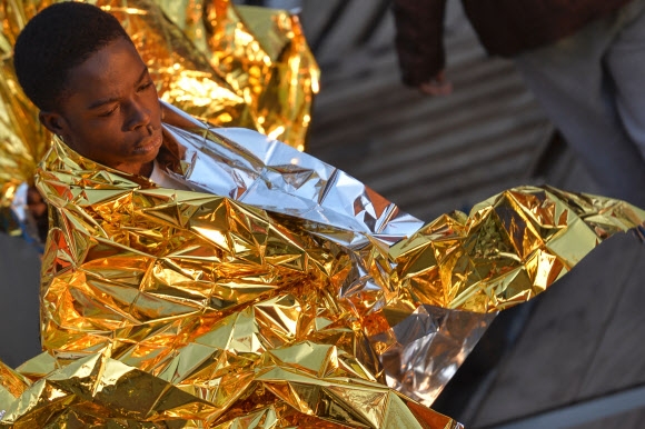 A man wrapped in a survival foil blanket rests aboard the Topaz Responder ship run by Maltese NGO Moas and the Italian Red Cross after a rescue operation of migrants and refugees on November 3, 2016, off the Libyan coast in the Mediterranean Sea.  사진=AFP 연합뉴스