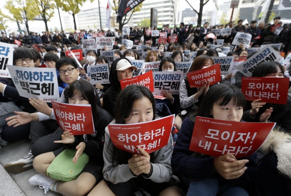 5일 광화문 광장에서 열린 ‘#내려와라 박근혜 2차 범국민행동’ 집회에 참가한 학생들이 박근혜 대통령 퇴진을 촉구하는 피켓을 들고 거리에 앉아 있다. AP 연합뉴스