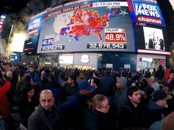 미국 뉴욕 시민들이 8일(현지시간) 타임스스퀘어의 한 대형 스크린에서 전국의 개표상황 중계를 살펴보고 있다. 뉴욕 AFP 연합뉴스