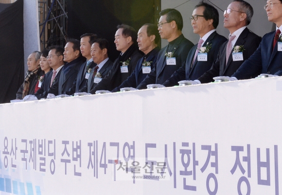 28일 서울 용산구 국제빌딩 제4구역 부지에서 열린 도시환경 정비사업 기공식에서 성장현(오른쪽 네 번째) 용산구청장이 축하 폭죽을 터뜨리기 위해 단추를 누르고 있다. 손형준 기자 boltagoo@seoul.co.kr