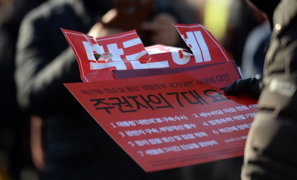 9일 서울 여의도 국회앞에서 열린 집회에 참석한 시민이 주권자의 7대요구가 적인 손피켓을 즐고 있다.   박지환 기자 popocar@seoul.co.kr
