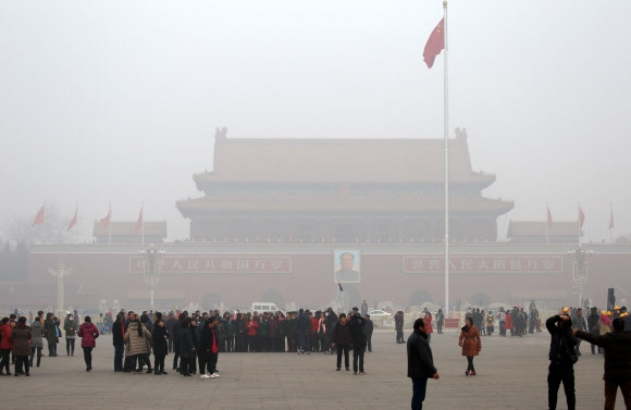 중국 베이징에 스모그 적색경보가 발령된 가운데 톈안먼에 관광객들이 마스크를 쓰고 관람하고 있다.  연합뉴스