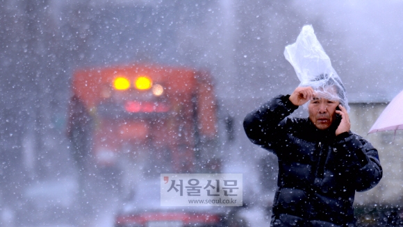 13일 서울 광화문 광장에서 한 시민이 봉지를 이용해 눈을 피하고 있다.  박지환 기자 popocar@seoul.co.kr