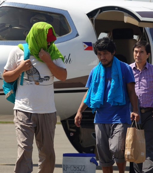 지난해 말레이시아 인근 해상에서 이슬람 무장단체의 습격을 받아 납치됐던 한국인 선장이 피랍 86일 만인 14일 무사히 풀려났다. 얼굴에 두건을 감은 선장(왼쪽)과 함께 풀려난 필리핀 선원이 필리핀 다바오에 도착해 비행기에서 내리고 있다. 다바오 EPA 연합뉴스