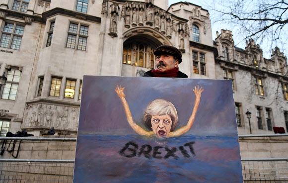정치풍자 예술가인 카야 마가 24일(현지시간) 영국 런던의 대법원 앞에서 테리사 메이 총리가 침몰하는 모습의 풍자화를 들고 시위를 벌이고 있다. 런던 EPA 연합뉴스