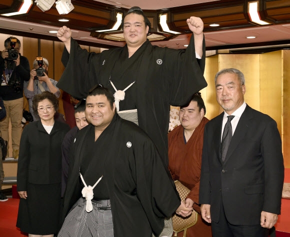 요코즈나에 오른 기세노사토가 마굿간 동료인 다카야수(아래) 등에 의해 옮겨지면서 의기양양하게 두 팔을 들어올리고 있다. 도쿄 AP 연합뉴스