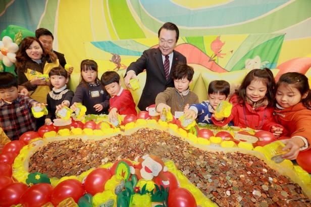 지난해 열린 ‘사랑의 저금통’ 전달식에서 노현송(가운데) 강서구청장이 아이들과 함께 모금함에 동전을 넣고 있다. 강서구 제공