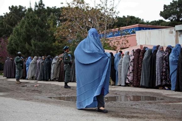 부르카를 입은 아프가니스탄 여성이 부르카와 니캅을 입고 줄을 선 다른 여성들 곁을 지나고 있다. AP연합뉴스