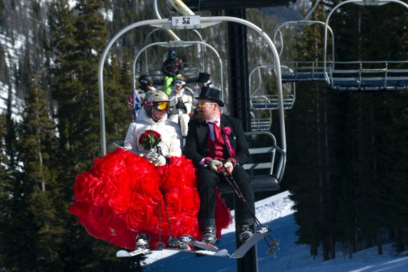 14일(현지시간) 미국 콜로라도주의 러브랜드 스키 코스에서 개최된 ‘제26회 밸런타인데이 산 정상 결혼식’에 브라운 부부가 결혼 10주년을 기념해 특별한 웨딩 촬영을 위해 리프트를 타고 산에 오르고 있다.   AFP 연합뉴스