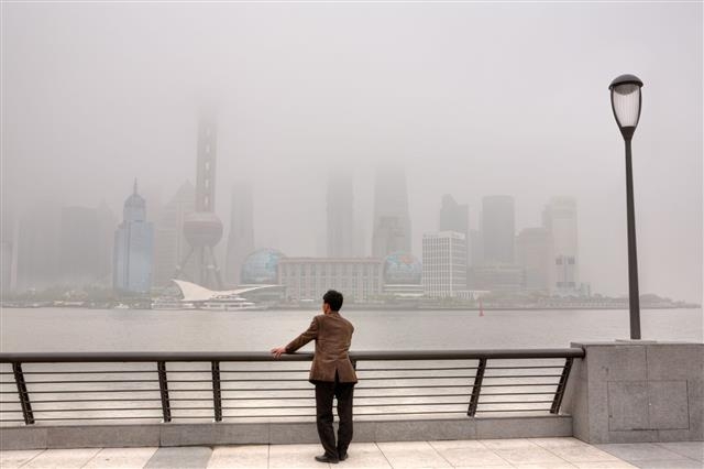 한 중국 남성이 대기오염으로 뿌옇게 흐려진 상하이 도심을 바라보고 있다. 출처 kr.123rf.com