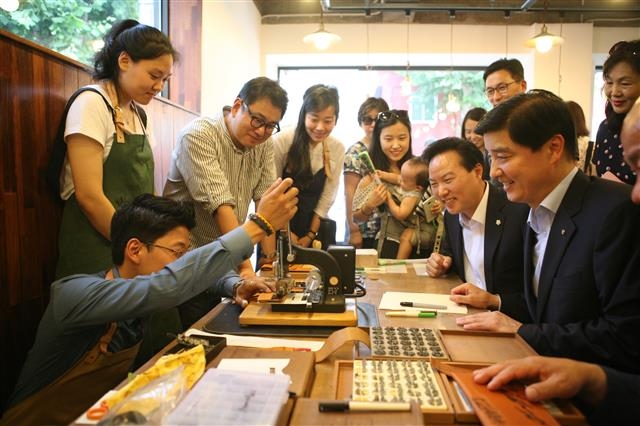 이해식(오른쪽) 서울 강동구청장이 가죽공예를 전문으로 하는 청년공방 1호점 ‘코이로’를 방문해 한 직원이 기계를 다루는 모습을 흥미롭게 바라보고 있다. 강동구 제공