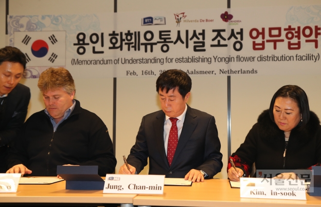 경기 용인시 투자유치단이 지난 16일 네덜란드 알스미어시에 있는 화훼경매장 플로라홀단드에서 네덜란드 대형 화훼그룹인 힐베르다 데 보어사와 원예유통단지 조성을 위한 업무협약을 체결했다. 정찬민(가운데) 용인시장과 힐베르다사의 게르트 얀 숀네벨트(왼쪽) 대표가 협약서에 서명하고 있다. 용인시 제공 