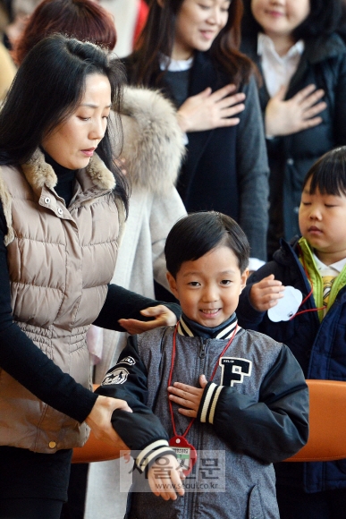 2일 서울 용산구 이태원초등학교에서 열린 입학식에서 한 신입생이 국기에 대한 경례식때 손의 위치를 몰라 헤매자 어머니가 고쳐주고 있다. 박윤슬 기자 seul@seoul.co.kr