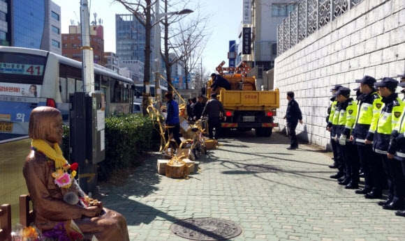 6일 부산 동구청 직원이 일본영사관 앞 소녀상 주변에 나붙은 불법 선전물을 철거하고 있다.  연합뉴스