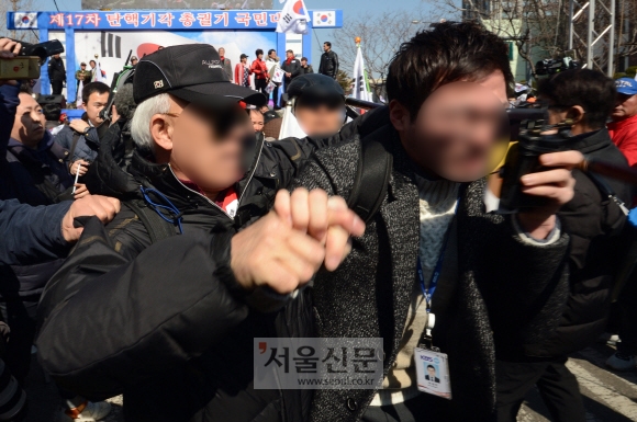 10일 서울 헌법재판소 앞 안국역에서 보수단체 회원이 탄핵이 인용되자 흥분한 상태로 기자를 폭행하고 있다.  박지환 기자 popocar@seoul.co.kr