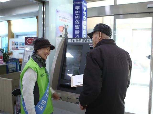 서울 영등포구청에서 근무하는 ‘안내도우미’가 한 구민의 무인민원발급기 사용을 돕고 있다. 영등포구 제공