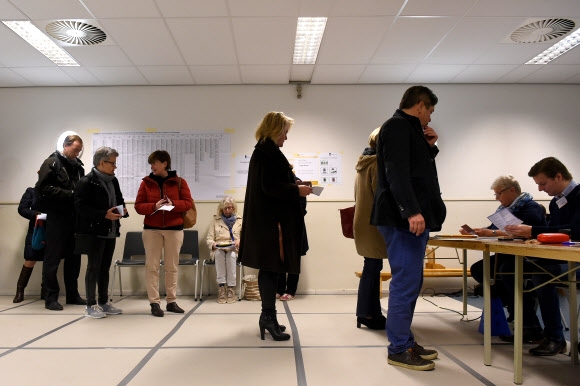 네덜란드 유권자들이 15일(현지시간) 헤이그의 한 투표소에서 투표용지를 받기 위해 줄을 서서 기다리고 있다. 하원 의원 150명을 뽑는 이번 선거는 오는 4~5월 열리는 프랑스 대선, 9월 독일 총선의 풍향계라는 평가를 받으면서 세계적인 관심을 모으고 있다. 헤이그 AFP 연합뉴스