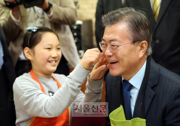 22일 서울 영등포구 대영초등학교 학생이 케익 만들기 실습을 마친 더불어민주당 문재인 전 대표 얼굴에 스티커를 붙이고 있다. 이종원 선임기자 jongwon@seoul.co.kr