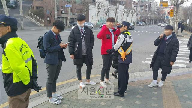 경찰관과 학부모, 지역 주민으로 이뤄진 ‘112 청소년 사랑회’ 회원들이 22일 서울 동대문구 휘경동의 한 대로변에서 아이들에게 금연 지도를 하고 있다. 바닥에는 학생들의 주머니에서 나온 라이터들.
