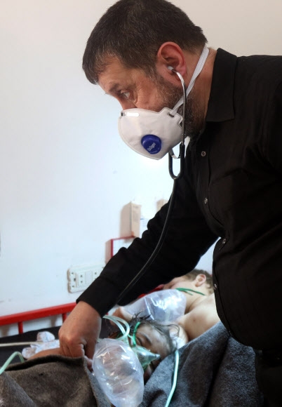 시리아 반군이 점령한 이들리브주의 칸셰이칸 주택가에 4일(현지시간) 화학무기를 사용한 것으로 의심되는 공습으로 지역 주민 최소 58명(어린이 11명 포함)이 사망한 가운데 한 의료요원이 유독 가스에 중독된 어린이를 진찰하고 있다. 시리아 인권관측소(SOHR)는 이번 공습이 시리아 정부군이나 러시아군의 소행이라고 주장했다. 칸셰이칸 AFP 연합뉴스