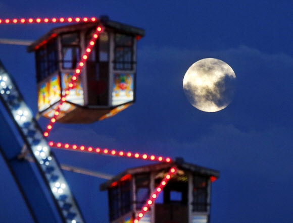 10일(현지시간) 독일 프랑크푸르트에서 열린 ‘디페메스(Dippemess)’ 축제에서 회전관람차 뒤로 보름달이 보인다. AP 연합뉴스