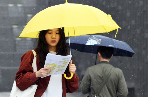 전국 곳곳에 비가 내리고 있는 17일 서울 서대문구 이화여자대학교에서 한 학생이 우산을 쓰고 시험공부를 하면서 걷고 있다. 2017. 4. 17. 박윤슬 기자 seul@seoul.co.kr