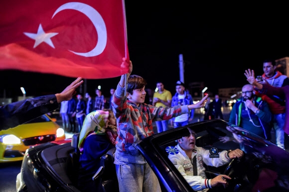 16일(현지시간) 밤 터키 이스탄불 탁심 광장에서는 국민투표 결과에 찬성하는 축하 집회가 열렸다. 사진은 한 소년이 터키 국기를 손에 들고 거리로 나온 시민들을 향해 손을 흔들고 있는 모습. 이스탄불 AFP 연합뉴스