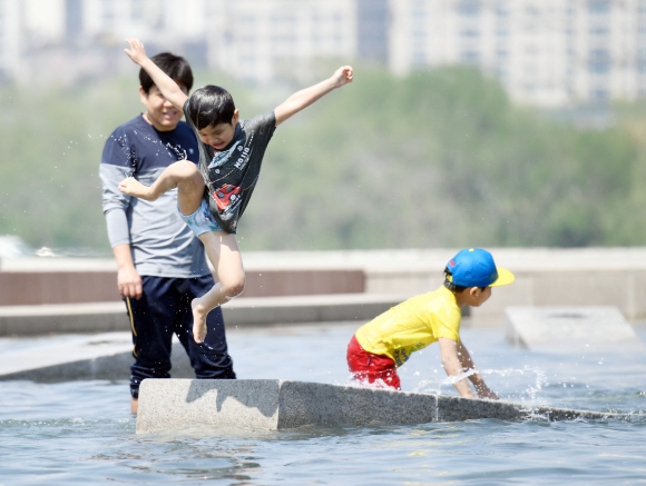 서울 낮 최고기온이 28도까지 올라가는 등 여름날씨를 보인 1일 서울 여의도 물빛공원을 찾은 시민들이 물놀이를 즐기고 있다.  정연호 기자 tpgod@seoul.co.kr