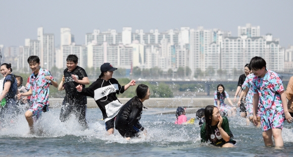 서울 낮 최고기온이 28도까지 올라가는 등 여름날씨를 보인 1일 서울 여의도 물빛공원을 찾은 시민들이 물놀이를 즐기고 있다. 정연호 기자 tpgod@seoul.co.kr