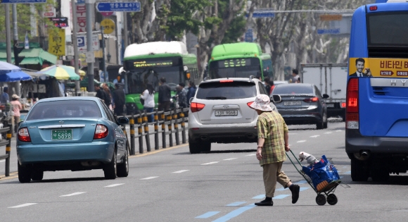2일 서울 영등포구 영등포시장사거리에서 한 노인이 짐수레를 끌며 차량의 통행이 많은 6차선 도로를 무단횡단하고 있다. 손형준 기자 boltagoo@seoul.co.kr