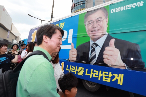 안철수 국민의당 대선후보가 4일 오후 경북 대구 동구 일대를 도보로 다니며 가진  ’걸어서 국민 속으로’ 유세에서 시민들과 기념촬영을 하는 안 후보의 옆으로 문재인 더불어민주당 후보의 선거유세차량이 지나가고 있다.  강성남 선임기자 snk@seoul.co.kr