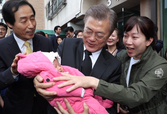 문재인 대통령이 10일 오전 서울시 서대문구 홍은동 자택을 나서며 생후 한 달 된 아이를 안아주고 있다.  안주영기자 jya@seoul.co.kr