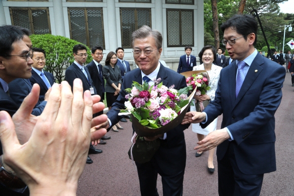 문재인 대통령이 10일 오후 부인 김정숙 여사와 청와대 본관에 들어서며 청와대 직원들로부터 꽃다발을 받고 악수를 나누고 있다. 오른쪽은 김경수 의원.  안주영 기자 jya@seoul.co.kr